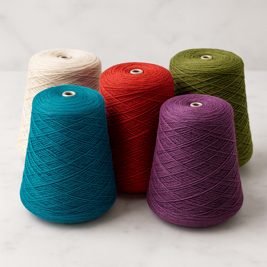 5 cones of Brown Sheep Nature Spun Yarn Cones in Fingering Weight. Jewel Tone solid colors on a white marble backdrop.