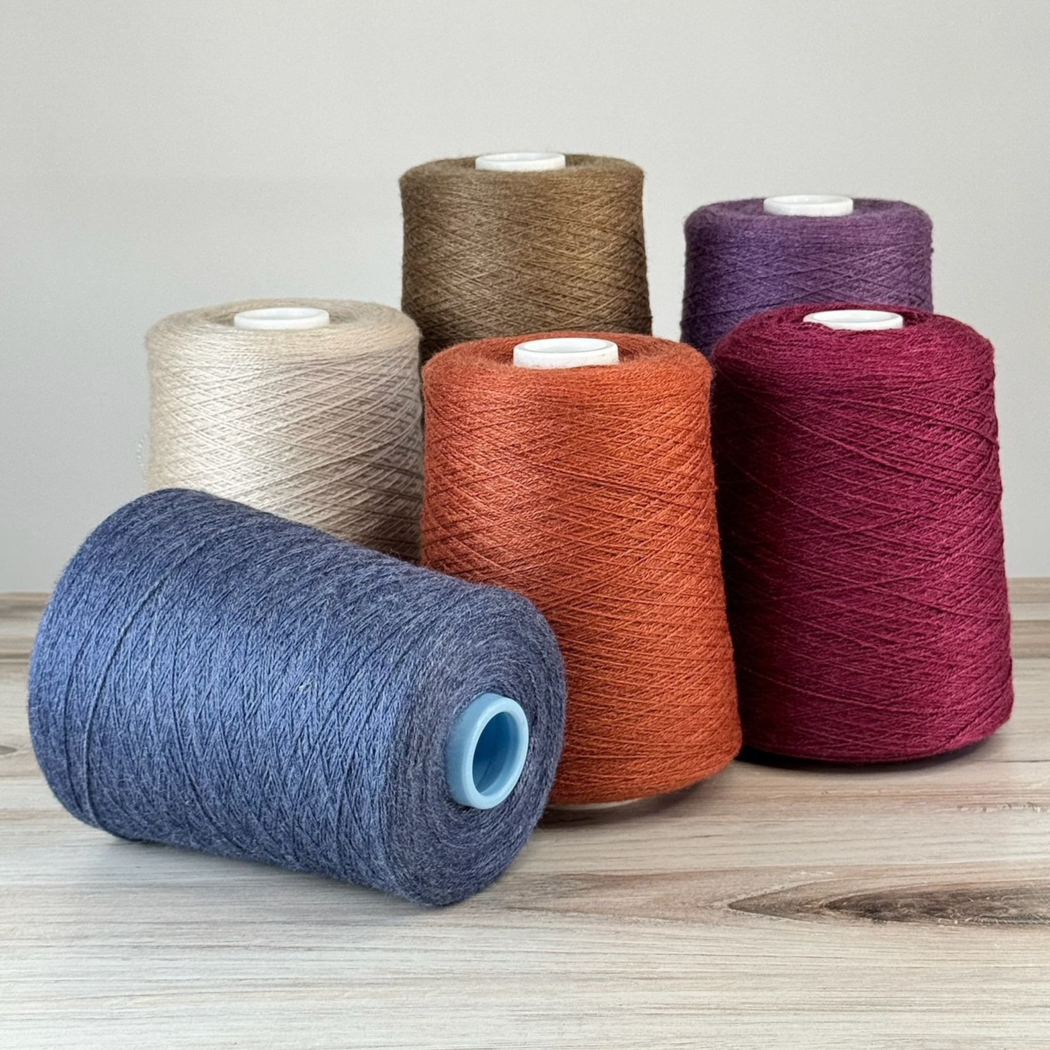 Vanilla, taupe, and orange cones with indigo rolled forward; 1 lb. cones, 2/18 lace, 4455 yards—balanced for warp or weft.