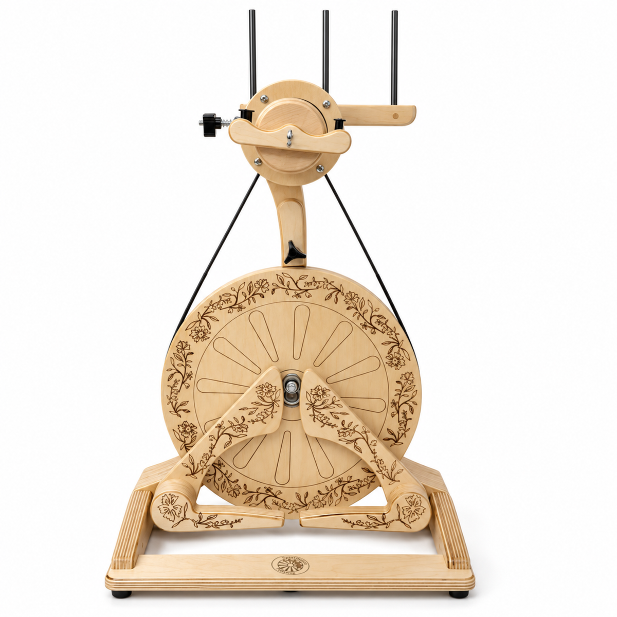 Front view of the SpinOlution Pollywog spinning wheel with decorative floral engraving, double treadles, and upright flyer assembly.