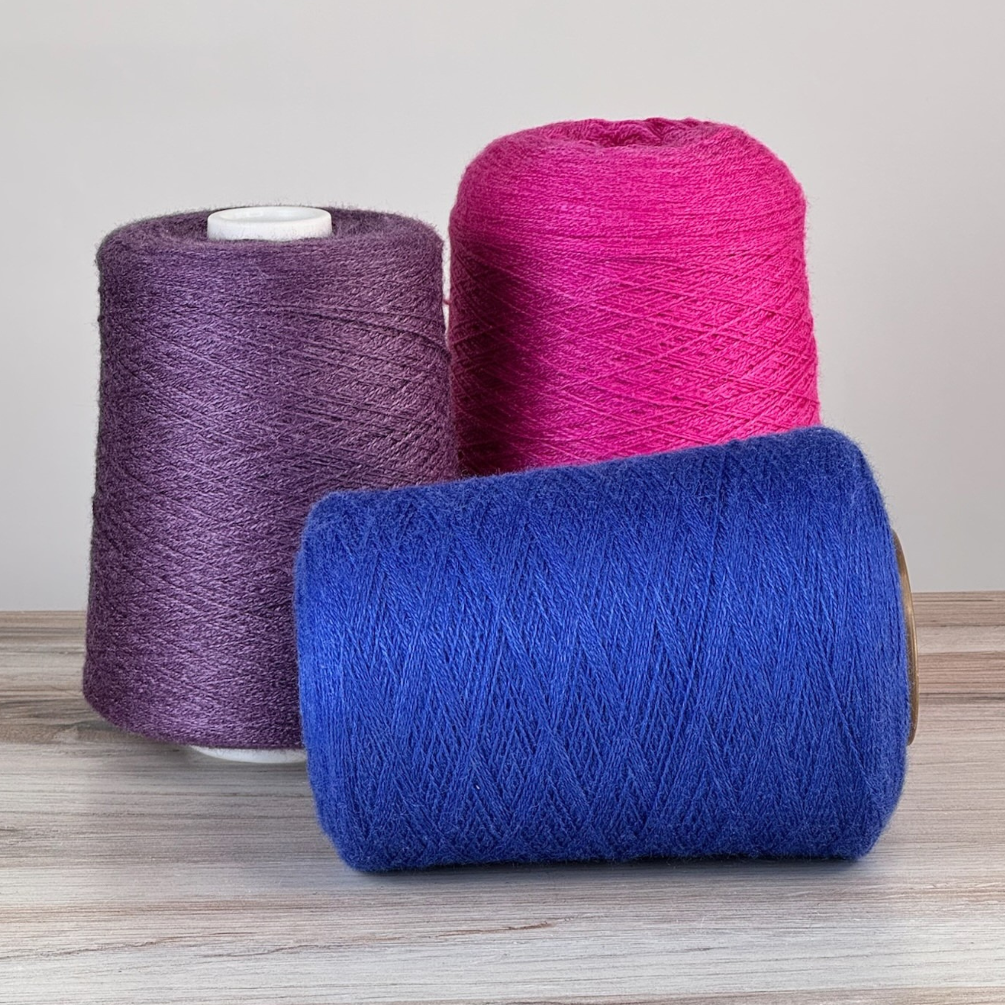 Magenta, purple, and royal cones with one royal laid on its side; 1 lb. cones, 2/18 lace (4455 yards), 50/50 tussah silk–superfine merino.