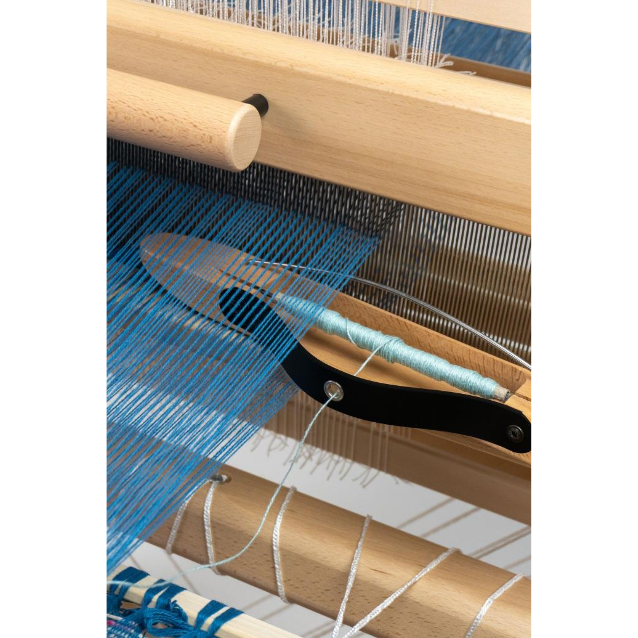 Close‑up of the David III’s cloth in progress, highlighting the shuttle race and blue warp threads.