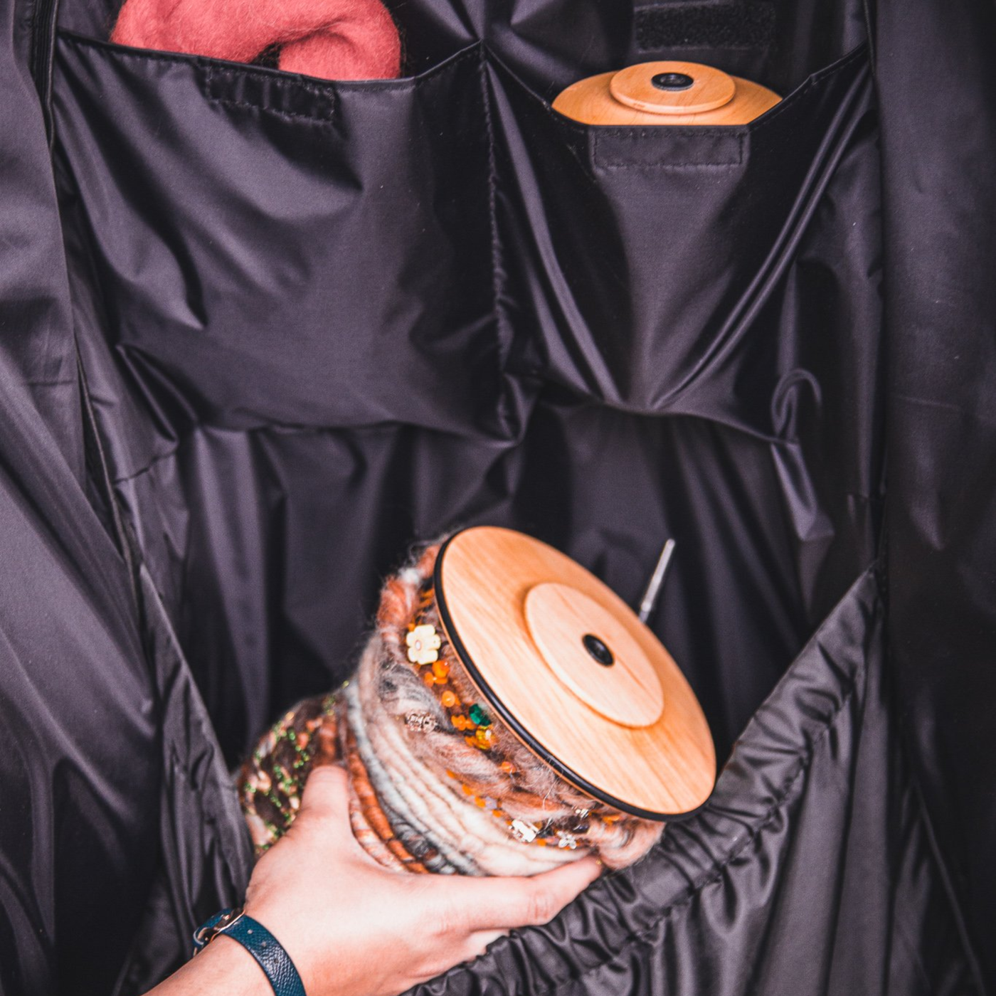 Hand placing a bobbin into Kromski Minstrel wheel bag interior pocket organizer—secure storage for spinning tools.