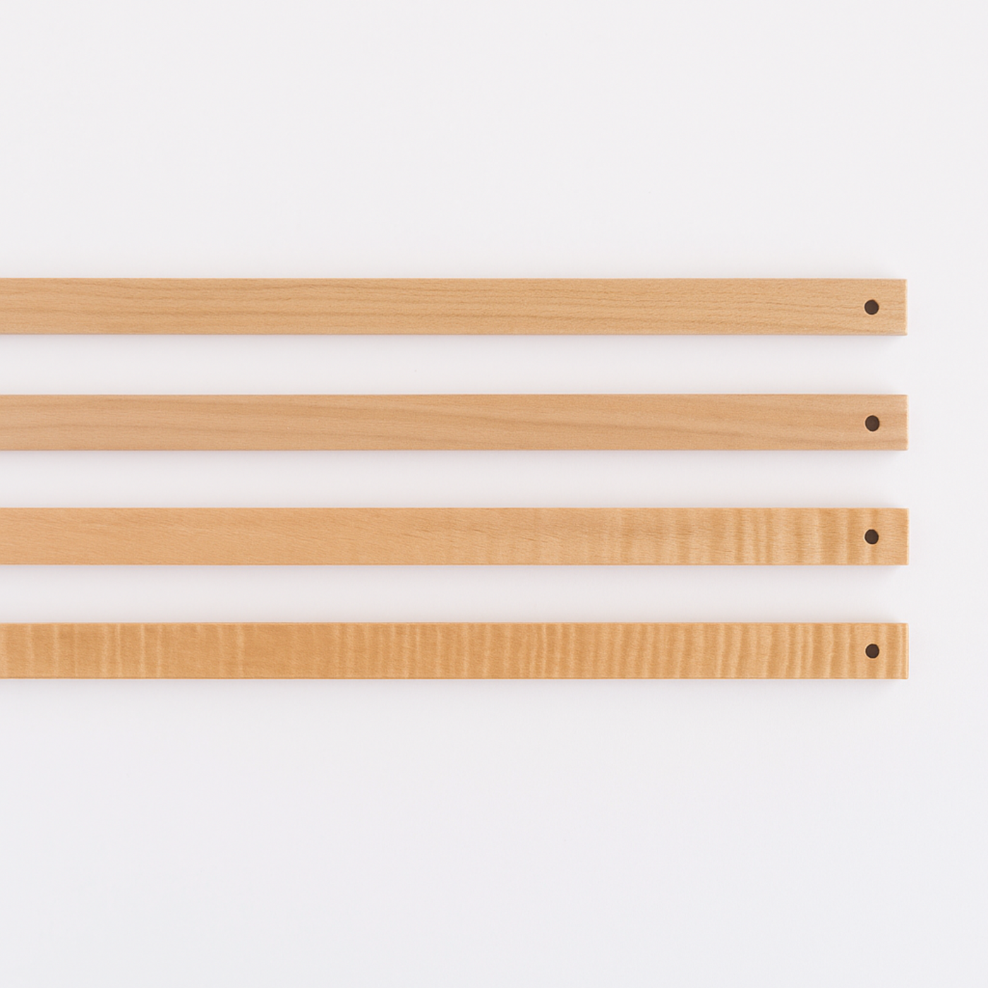 Three Leclerc Lease Sticks laid flat, showcasing smooth maple wood grain, lacquer finish, and drilled ends for loom tie-on