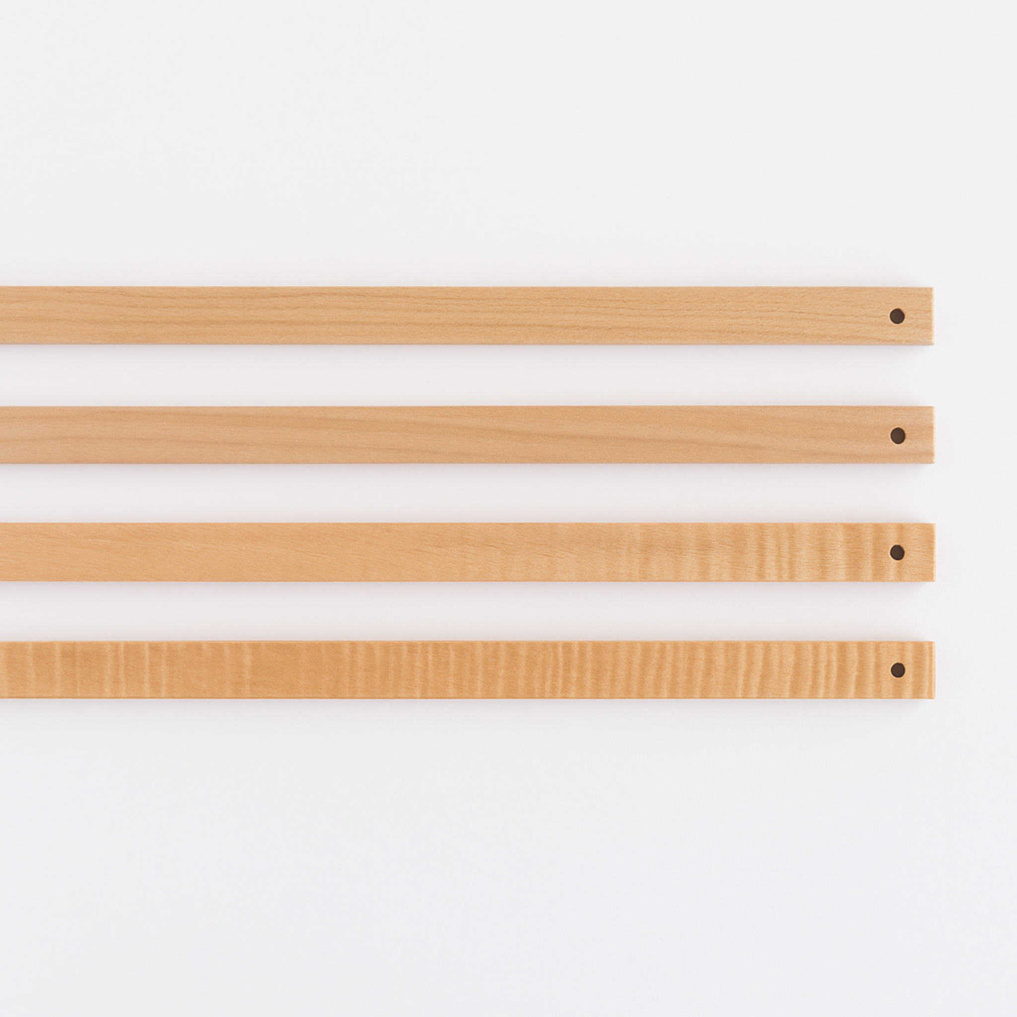 Three Leclerc Lease Sticks laid flat, showcasing smooth maple wood grain, lacquer finish, and drilled ends for loom tie-on