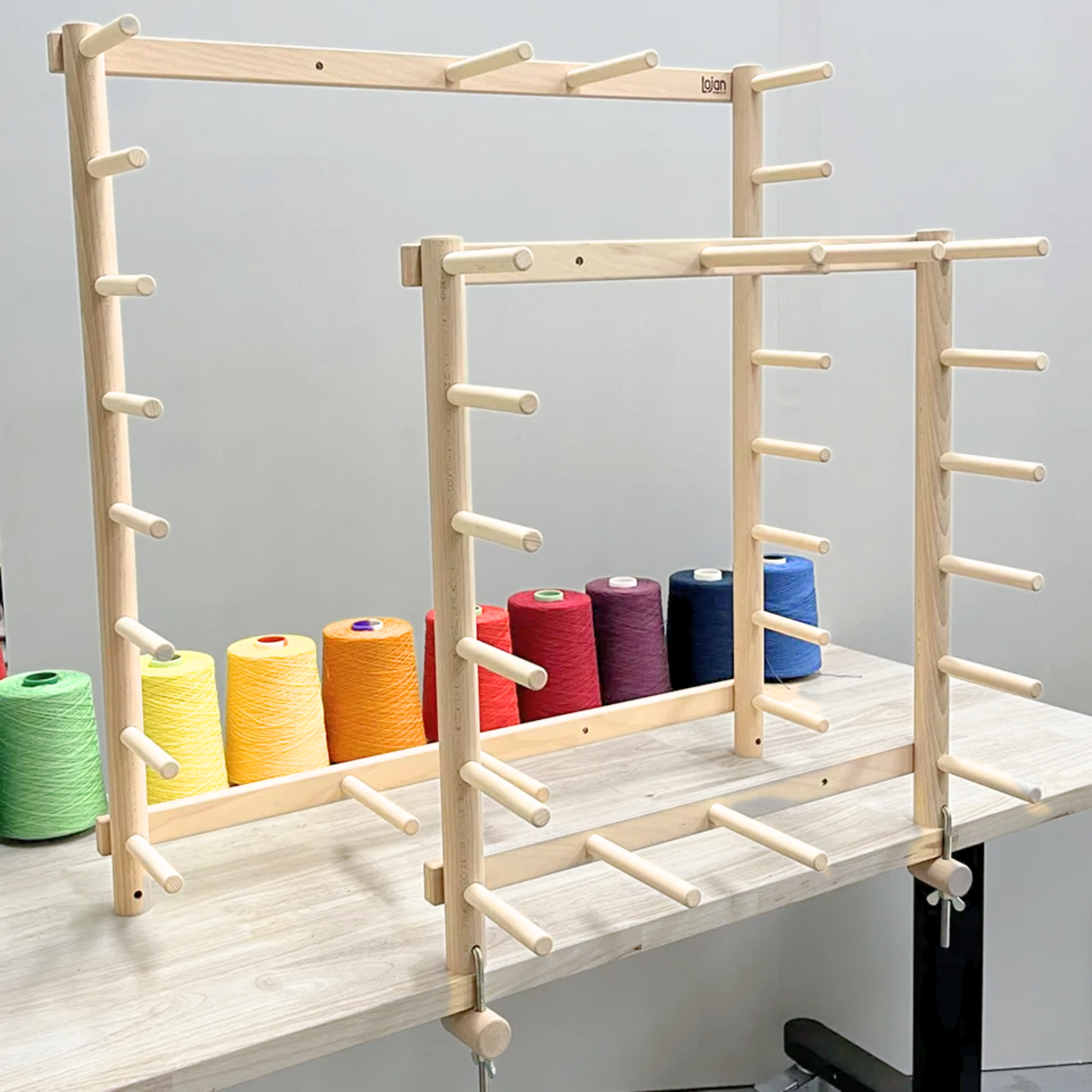 Lojan Warping Frames in 7-yard and 13-yard sizes on a table with colorful yarn cones in background.