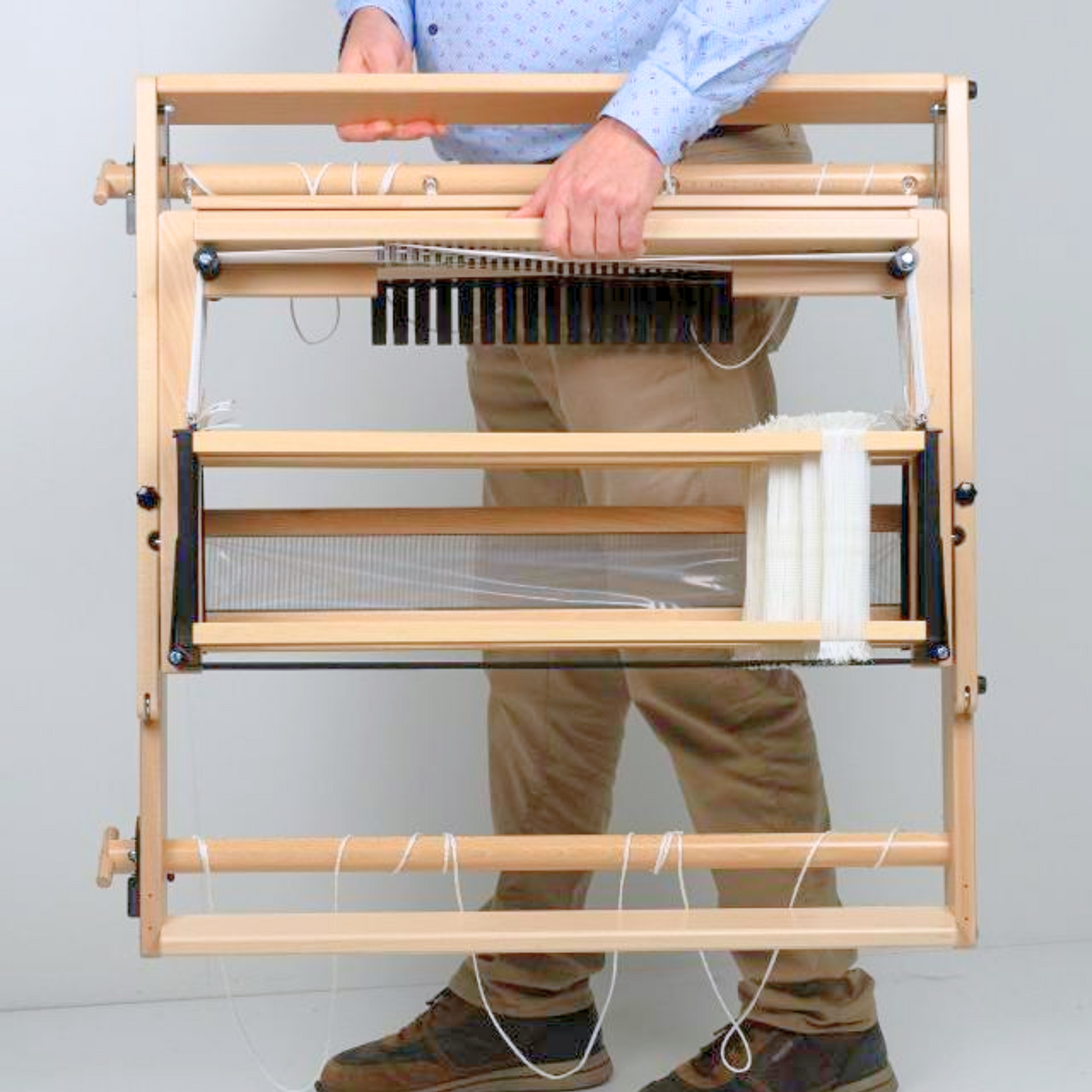 Folded Louët Jane table loom being carried easily, emphasizing compact, travel‑friendly design.