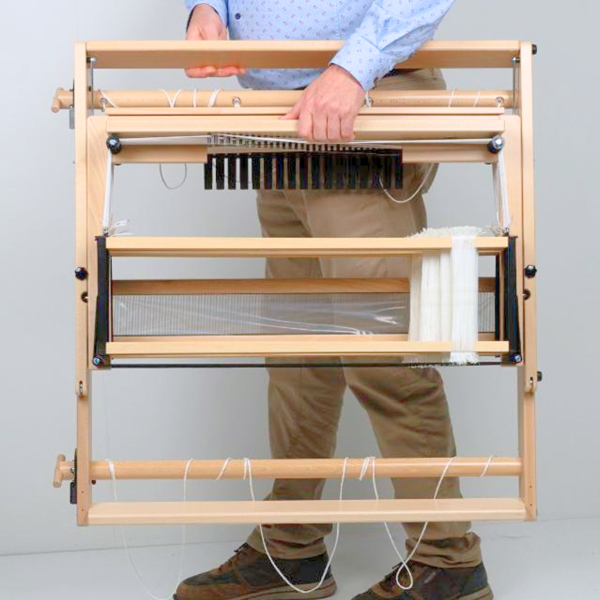 Folded Louët Jane table loom being carried easily, emphasizing compact, travel‑friendly design.