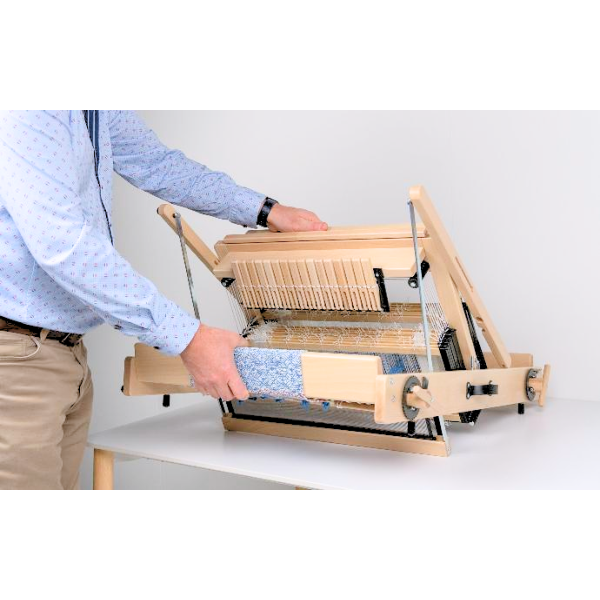Person folding the Louët Jane loom flat for storage or travel, illustrating quick‑collapse action.