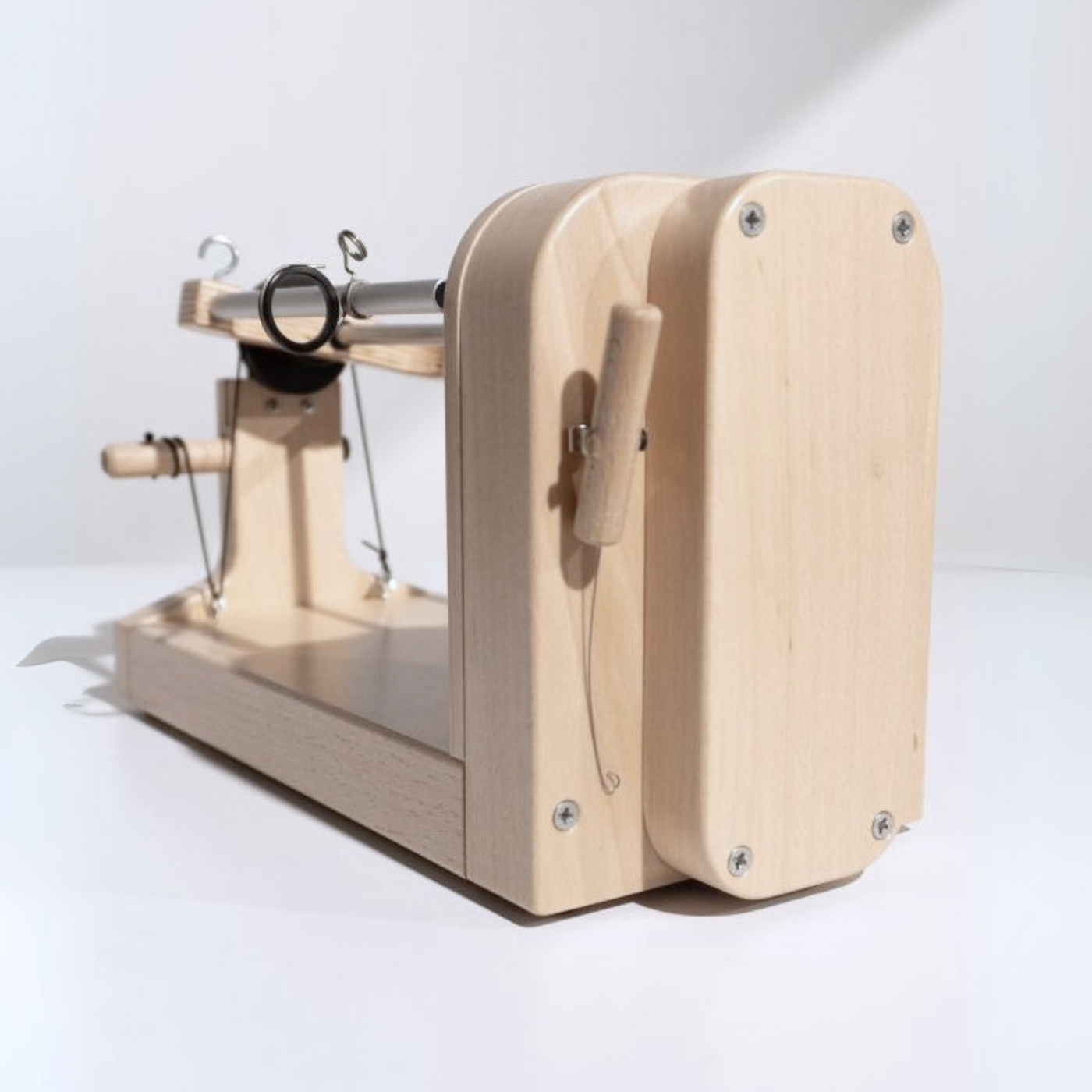 Rear view of the Louet Jenn-E Electric Spinning Wheel showcasing its compact design, smooth wooden finish, and back-mounted threading hook.