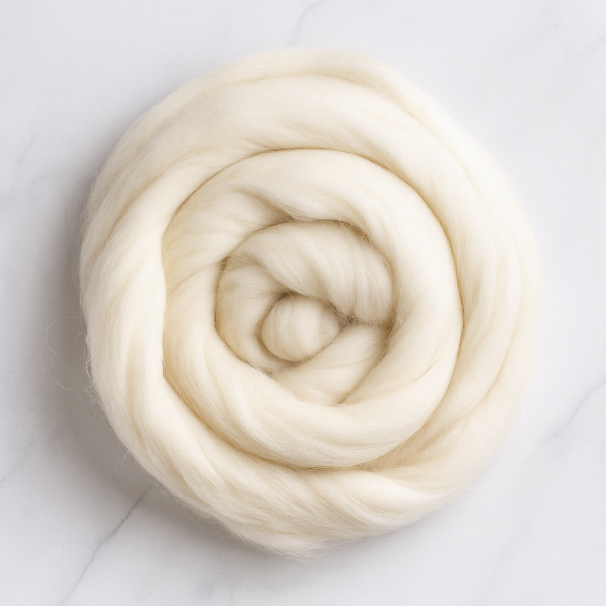 Undyed 18.5-micron merino wool top coiled on a light marble surface, showing soft, fine fiber for spinning or felting.