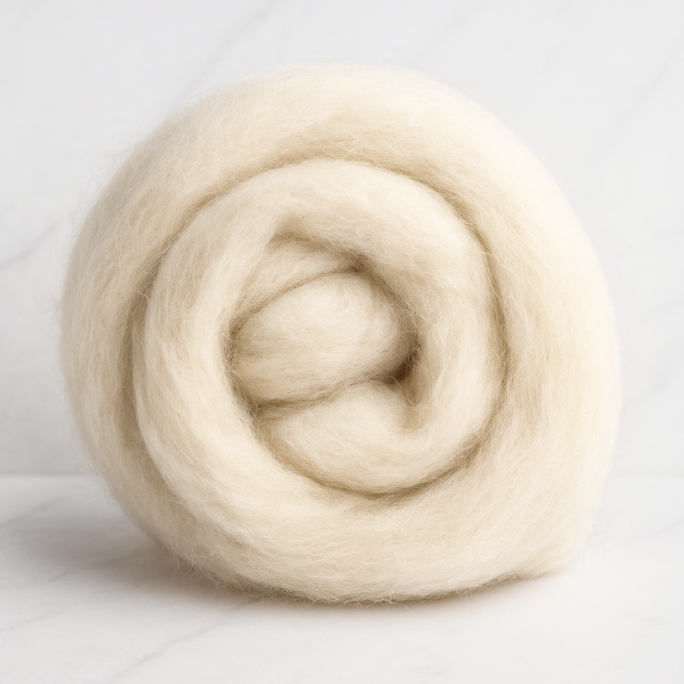 Coiled bundle of 19-micron carded Merino wool sliver, natural undyed, on a marble background showing soft airy texture—ready for spinning, felting, or dyeing.