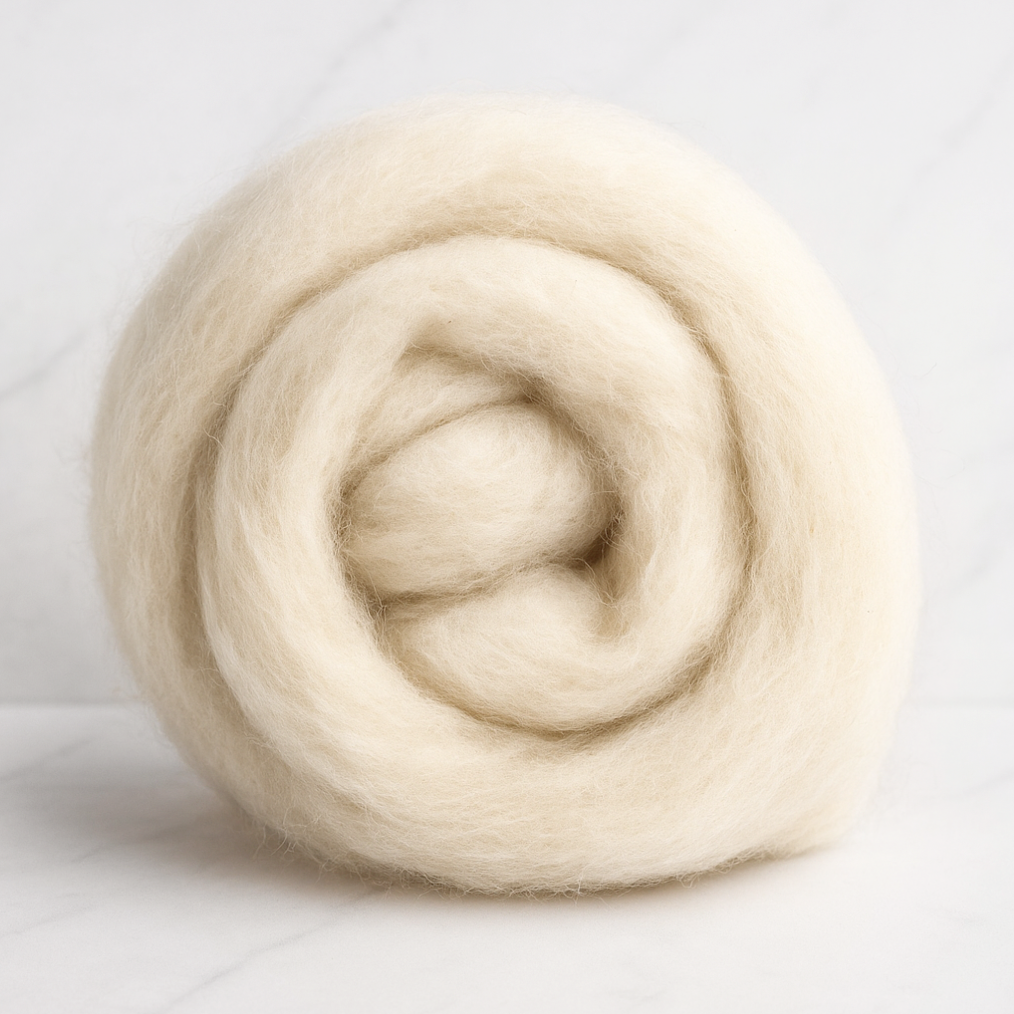 Coiled bundle of 19-micron carded Merino wool sliver, natural undyed, on a marble background showing soft airy texture—ready for spinning, felting, or dyeing.
