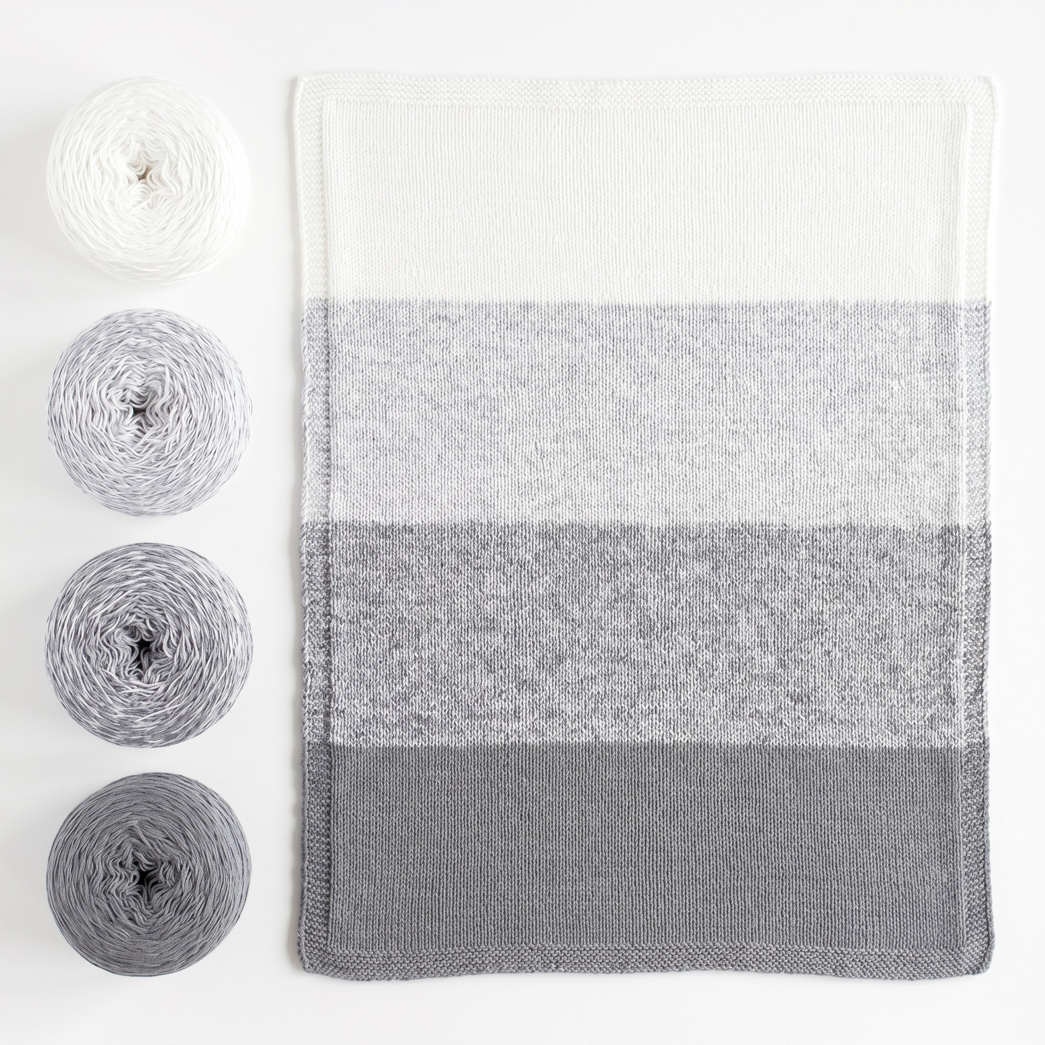 Revolution Fibers Baby Bloom Helios Gray baby blanket kit with matching gray yarn cakes and finished knit blanket.