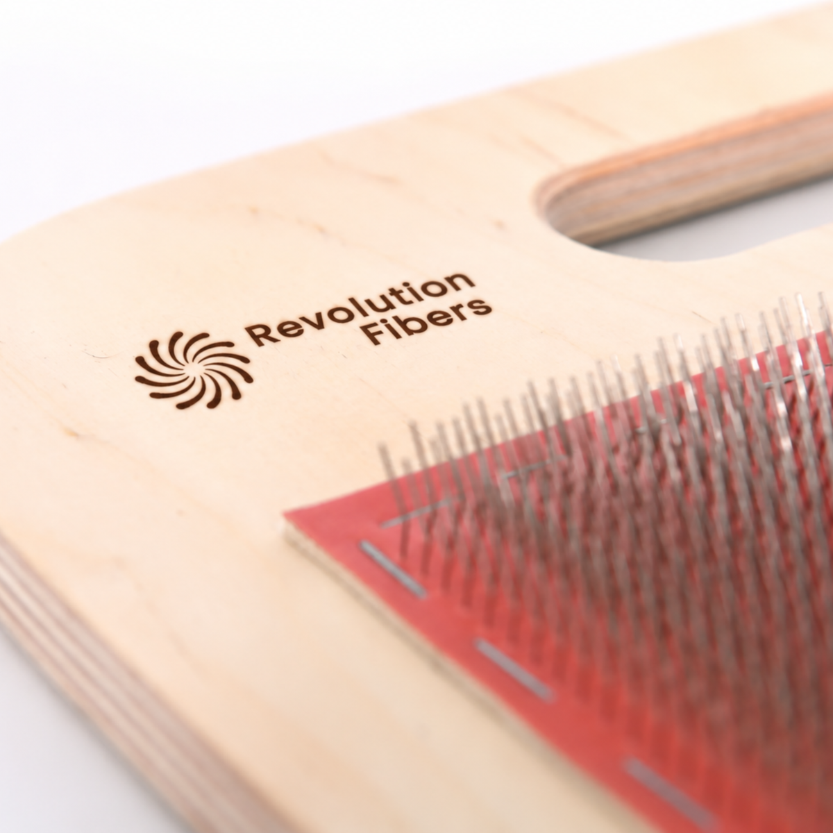 Close-up of the engraved Revolution Fibers logo and 108 TPI red carding cloth on the wooden blending board.