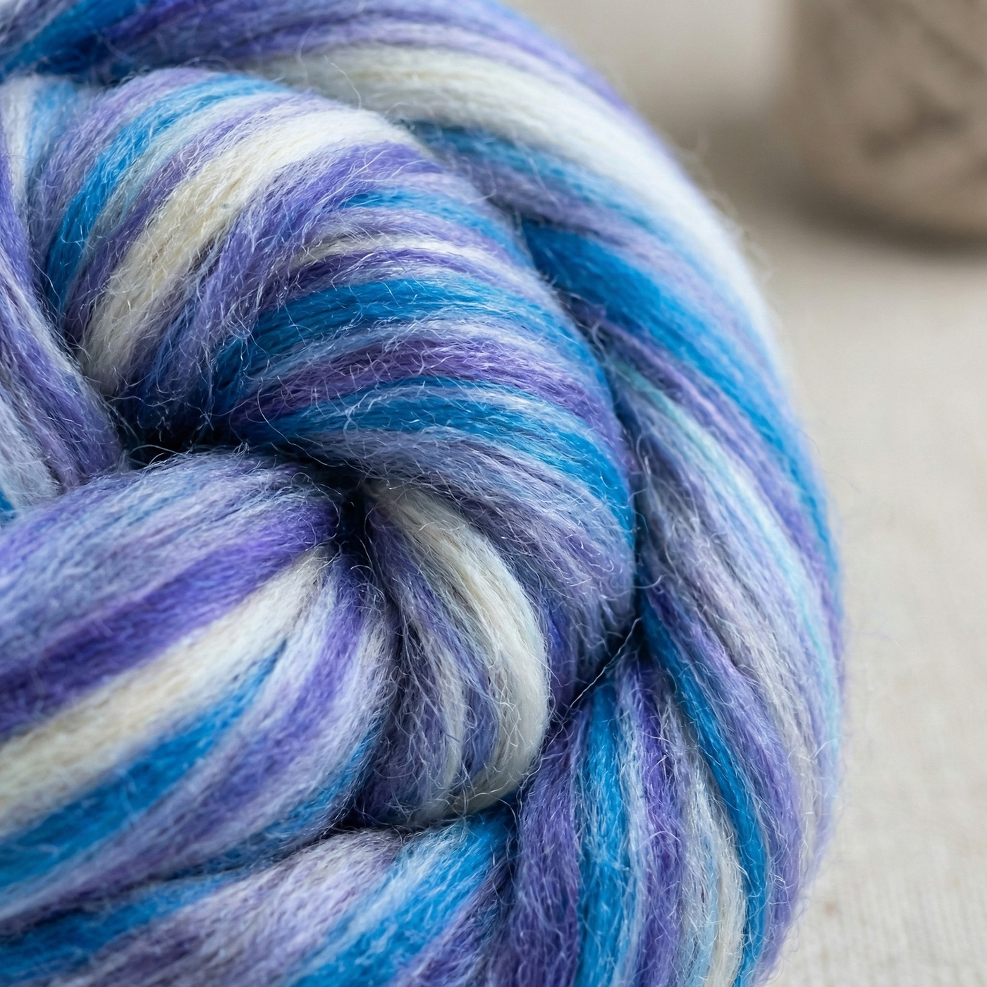 Macro close-up of Constellation Range roving showing merino–tussah silk texture, halo, and blue-lavender-cream color blending.