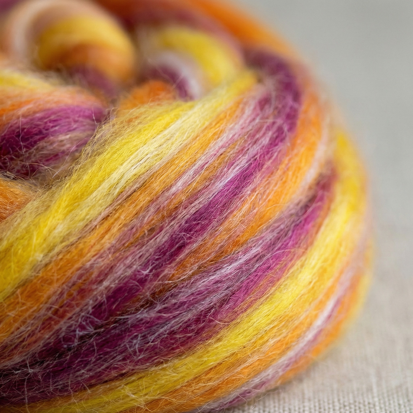 Macro close-up of Constellation Range roving showing merino–tussah silk texture and warm gold-yellow-magenta tonal blending.