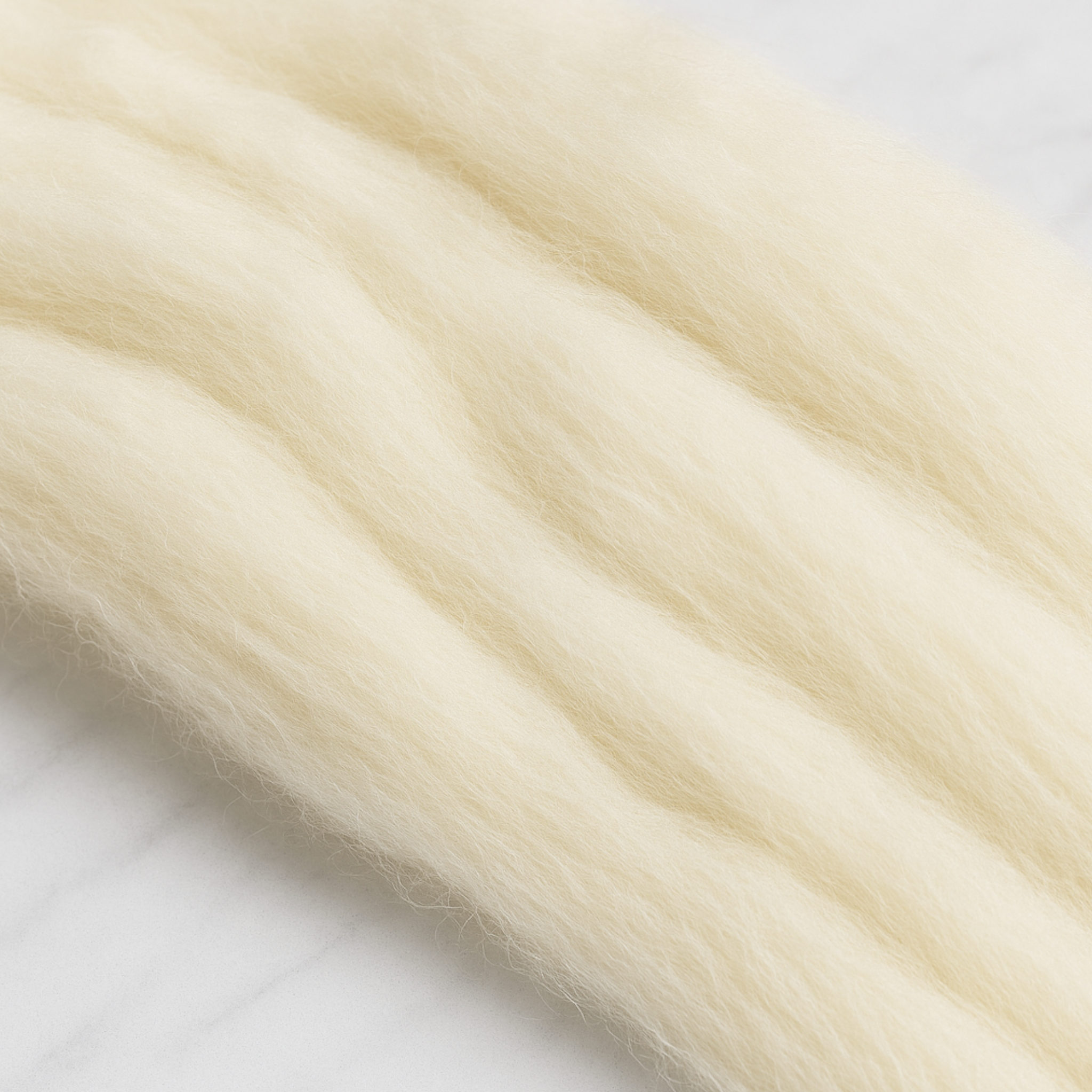 Close-up of Revolution Fibers Targhee wool combed top showing airy matte texture and soft loft, undyed cream fiber for hand spinning and felting.