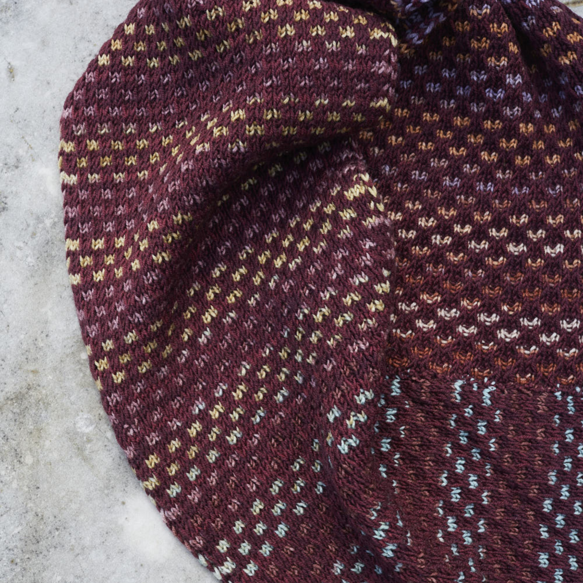 Folded view of the Saman Cowl in Harvest Black Grape paired with Uneek 3036, highlighting the deep plum palette.